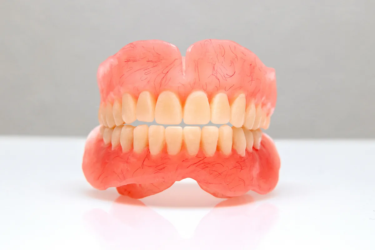 Snap-on dentures being cleaned with a toothbrush.