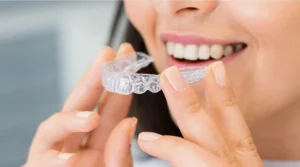 Braces vs. Clear Aligners: Which is Best for Your Boynton Beach Smile? 1 Braces vs. clear aligners: woman smiling while using a clear dental aligner for teeth straightening